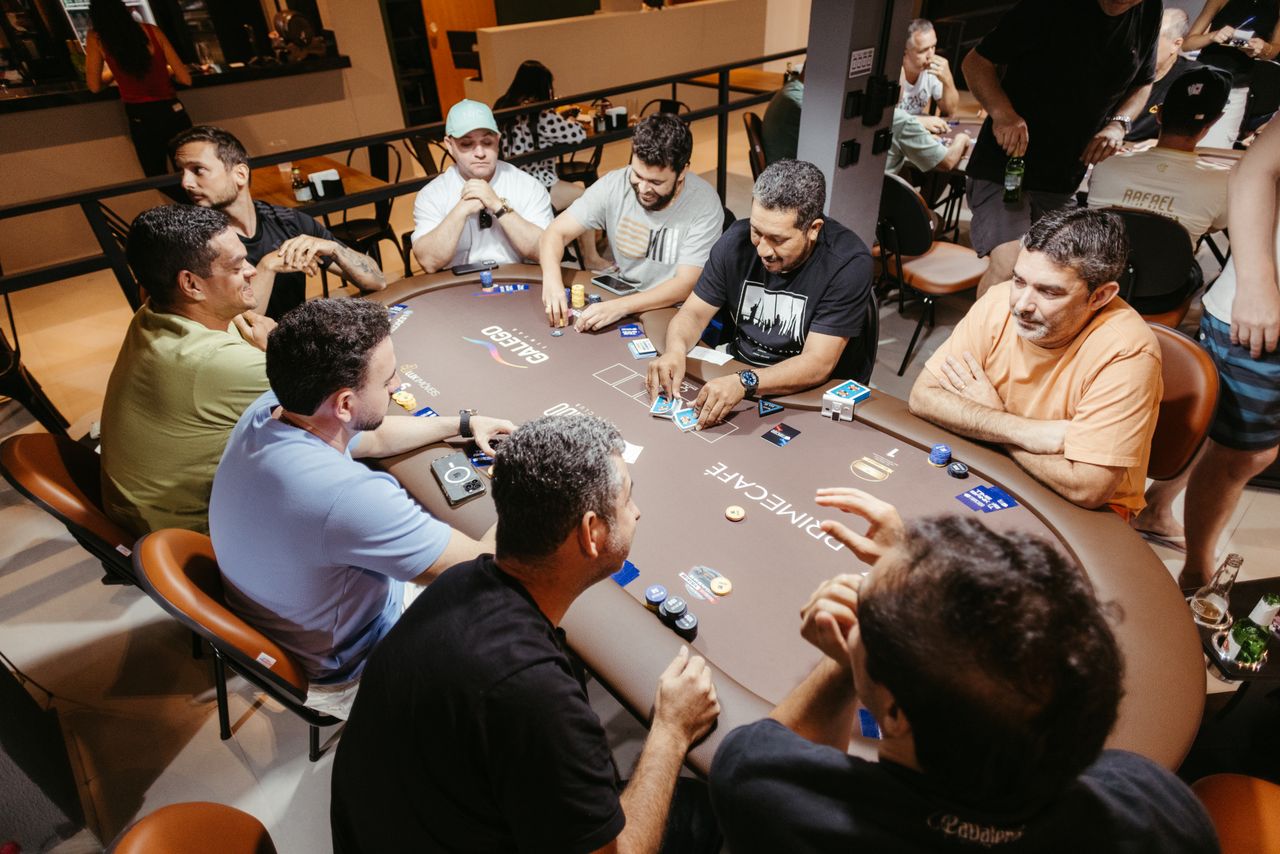 gallery-3 Group of men engaged in a poker game at an indoor setting, showcasing social interaction.